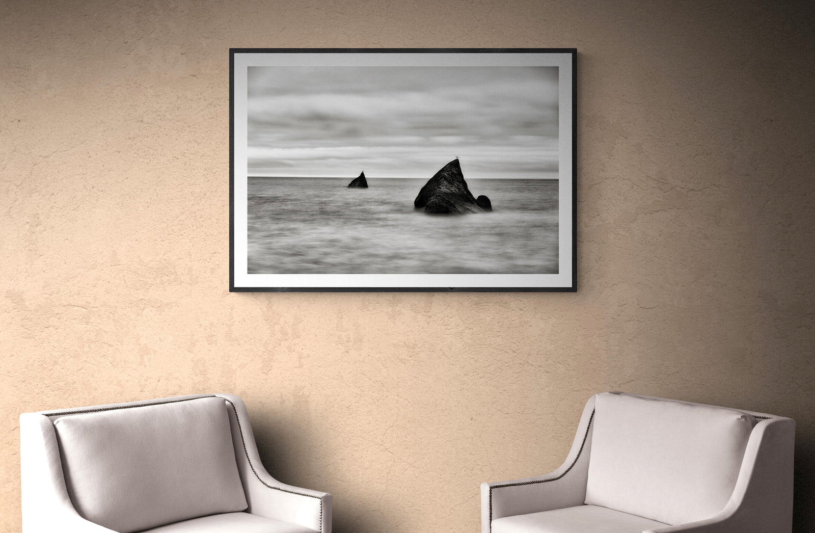 two seagulls sitting on rocks in the sea