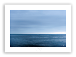 An image of a boat on the sea at the horizon line. Blue sea and blue clouds in a calm weather. 